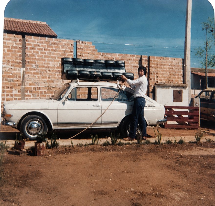 Foto antiga de 1981: jovem estofador amarrando estofados no teto de um Volkswagen para entrega